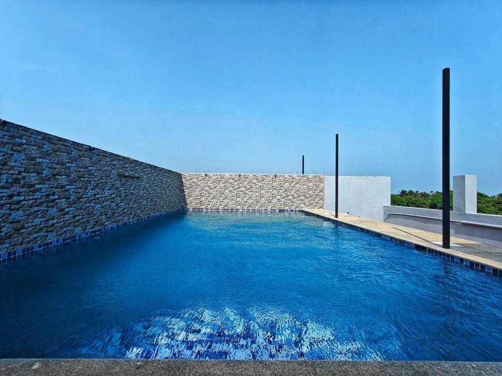 a large blue swimming pool with a brick wall at PV Tower - Auro Beach in Kuilapayam