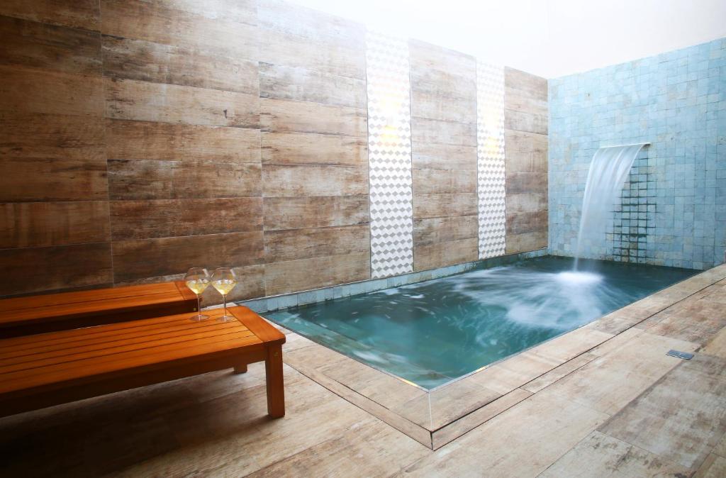 bañera de hidromasaje con banco y fuente de agua en Zaya Motel Premium, en Florianópolis