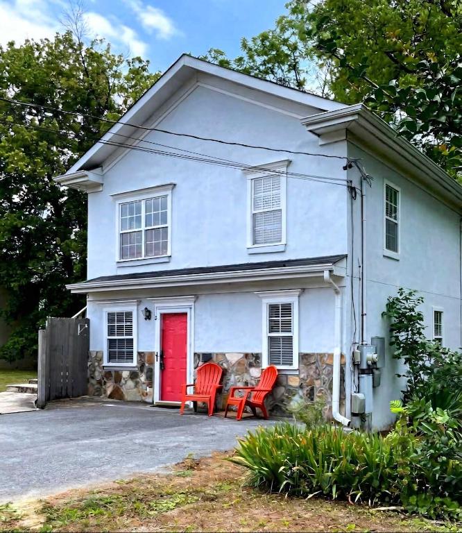 a white house with a red door and two chairs at Red Bank Cozy Nest in Chattanooga