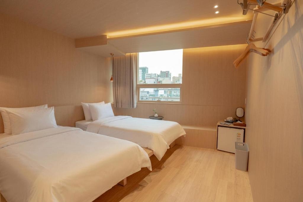 a hotel room with two beds and a window at yulstay in Seoul