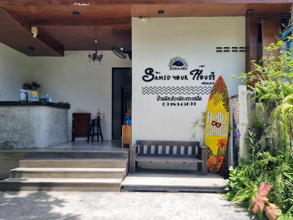 a building with a bench and a surfboard on the wall at Samed Your House in Ko Samed