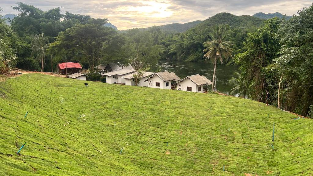 a group of houses on top of a green hill at ริมแควโฮมสเตย์ กาญจนบุรี in Ban Pong Pat