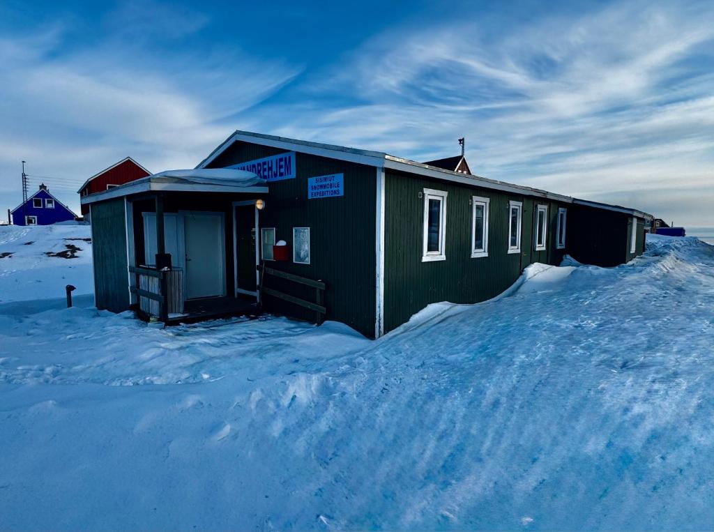 a building in the snow with snow around it at Kammak Hostel Sisimiut in Sisimiut