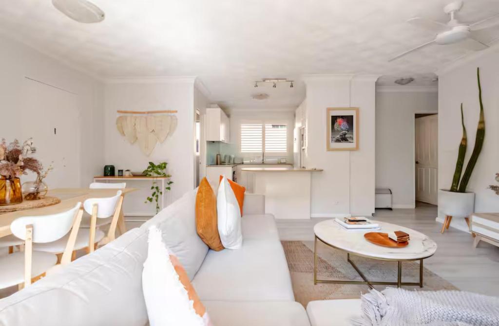 a white living room with a white couch and a table at Lovley sunlit apartment walking distance to Cronulla mall and Cronulla Beach in Cronulla