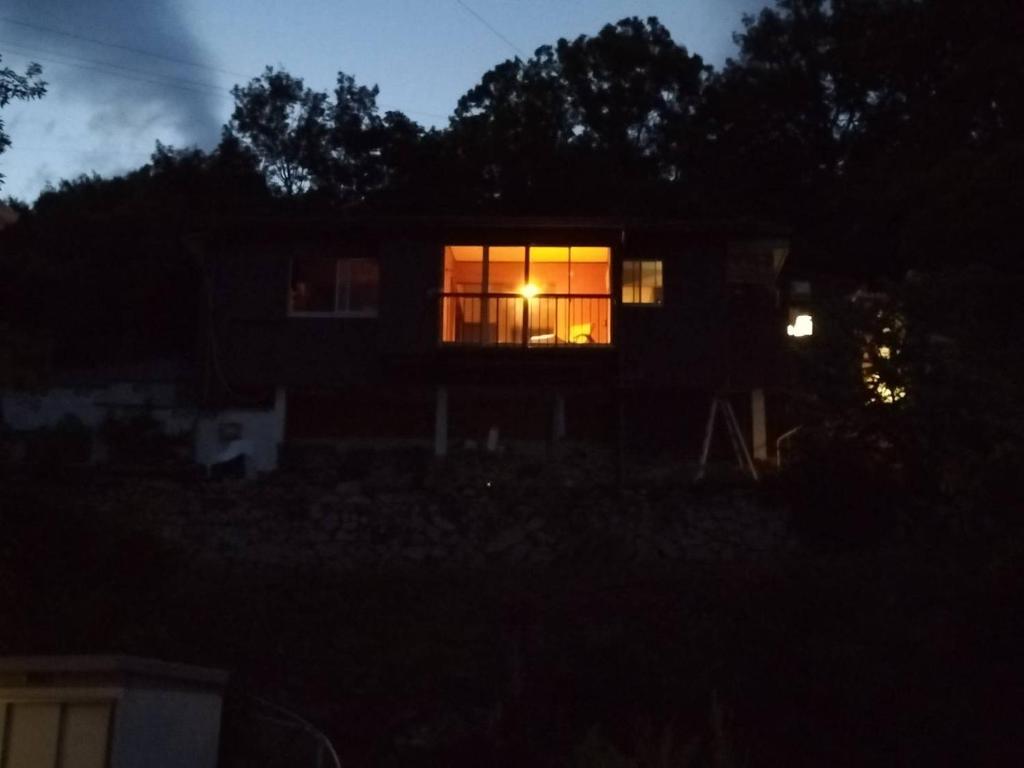 a house with a lit window at night at Kingfisher Lodge in Shodoshima