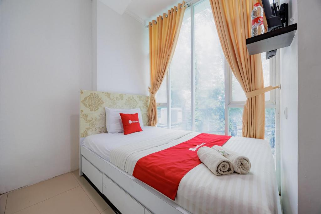 a bedroom with a bed with red pillows and a window at RedDoorz Near MRT Bendungan Hilir in Jakarta