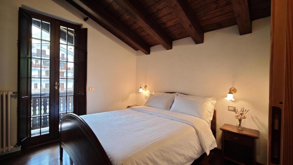a bedroom with a bed with white sheets and windows at Le Perce Neige in Morgex