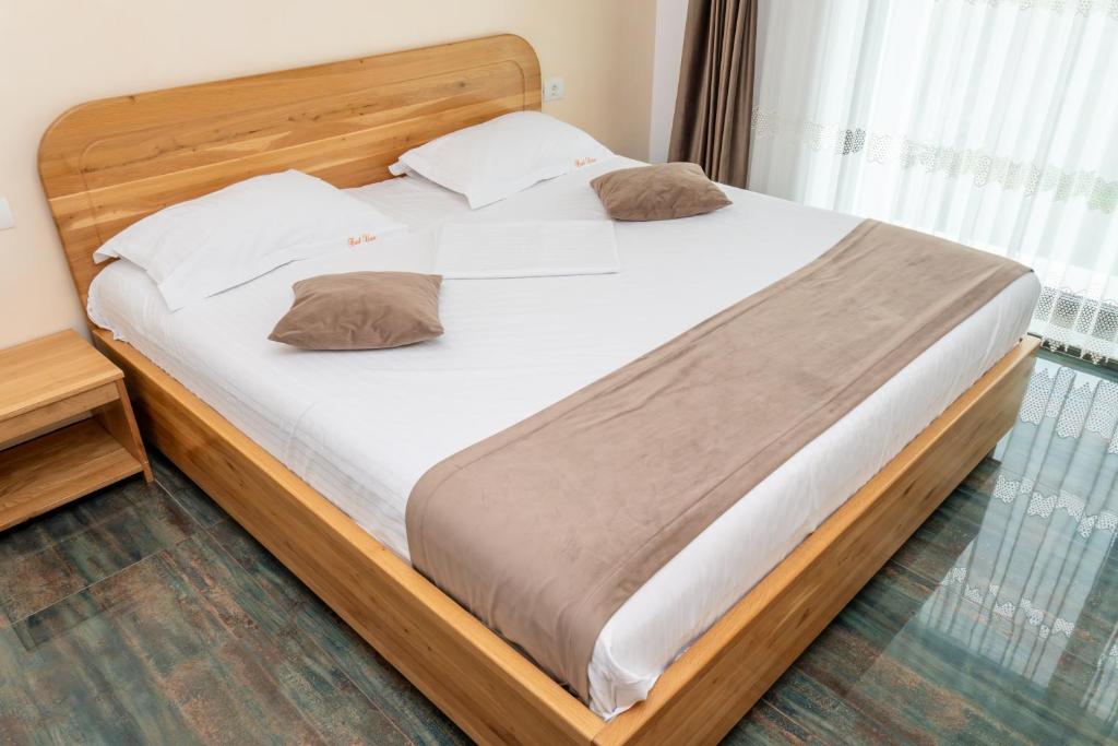 a large bed in a bedroom with a wooden headboard at Hotel Victor in Mamaia