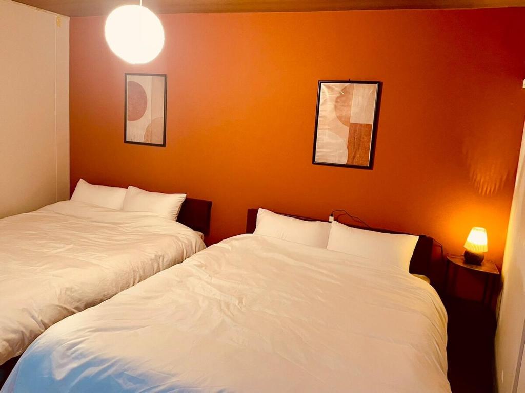 two beds in a room with orange walls at 結莉の宿 高槻 in Takatsuki