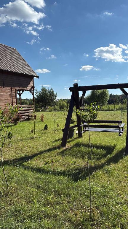 a park bench in a field with a building at Orla polana in Gorczyca