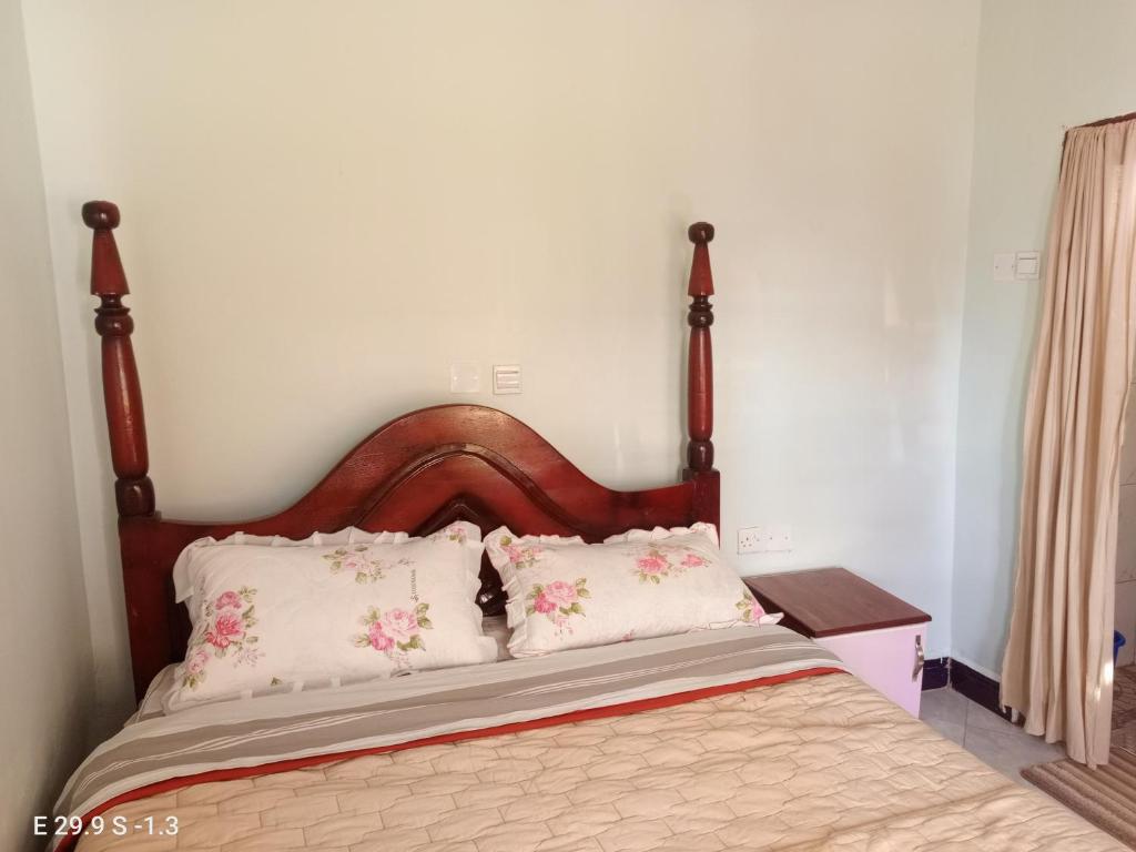a bed with a wooden headboard and two pillows at WYCLIFF BnB in Chabahinga