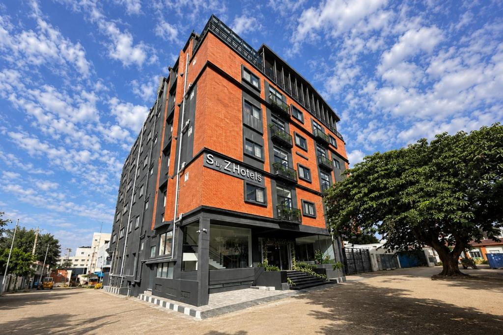 a tall brick building on a street with a tree at S by Z Hotels, HSR in Bangalore