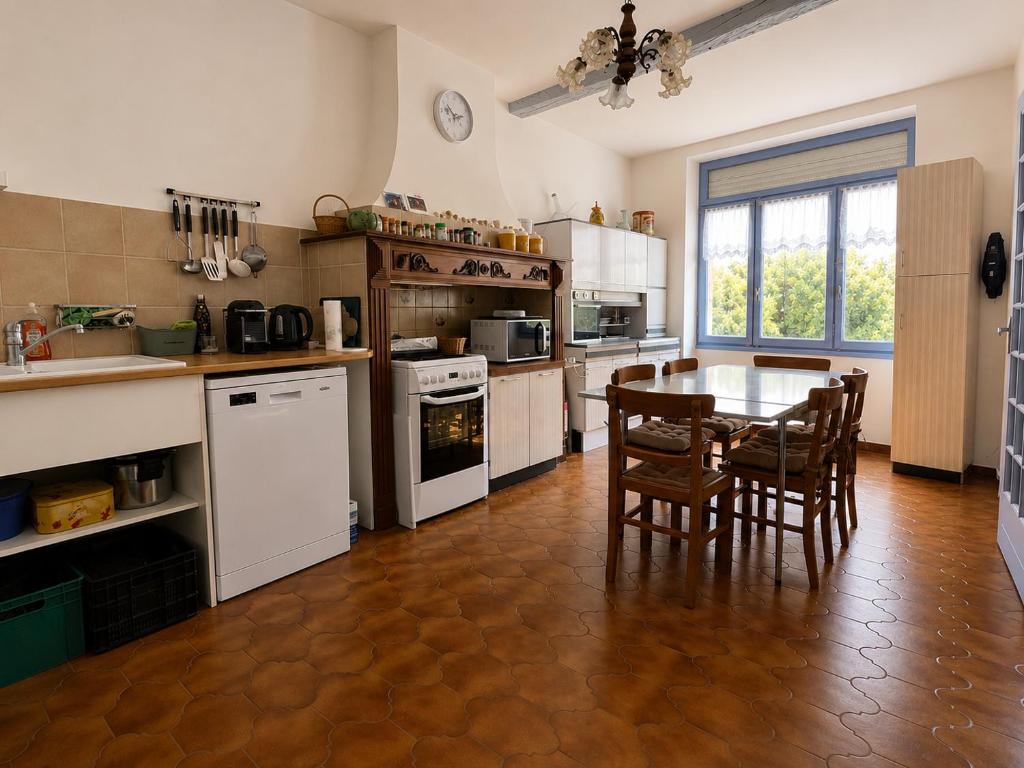 a large kitchen with a table and chairs in it at La maison boîte à gâteaux in Lapalme