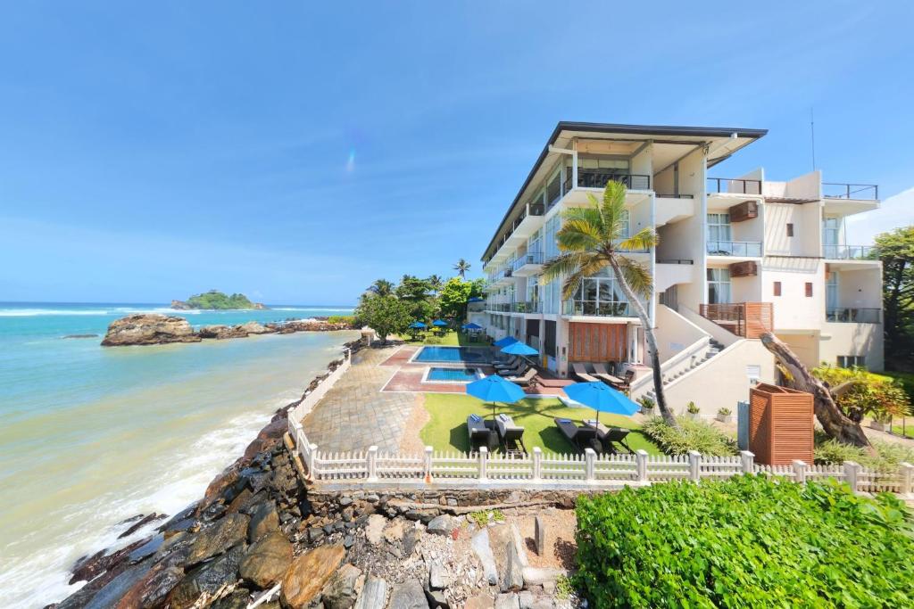 a building on the beach next to the ocean at Garton's Cape in Ahangama