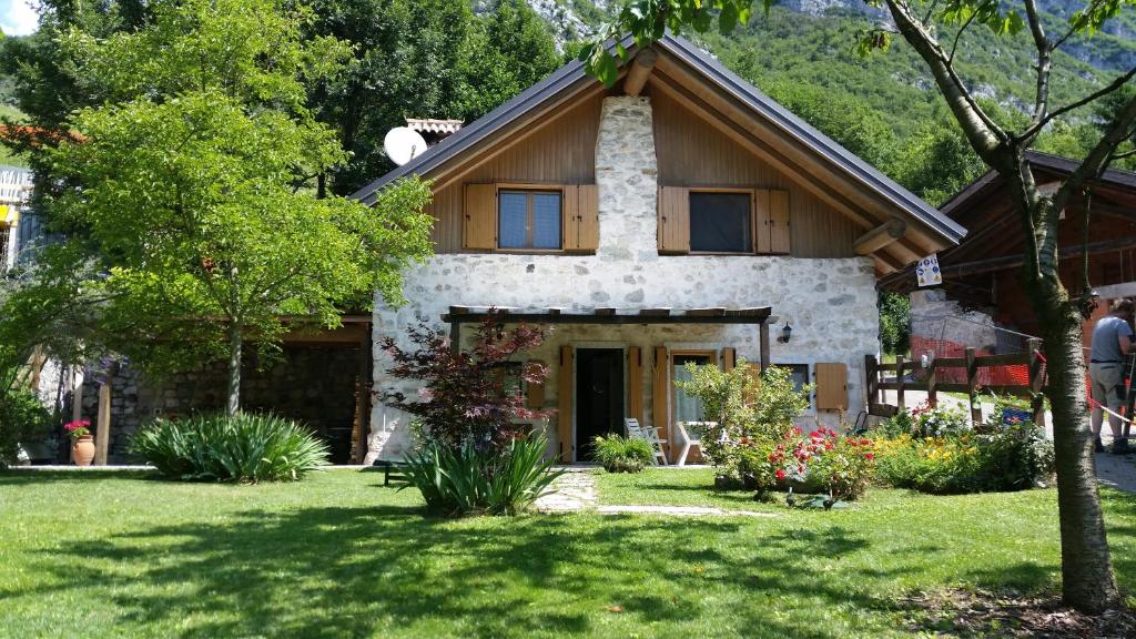 a house with a grassy yard with trees and flowers at Chalet La Nos in Molina di Ledro
