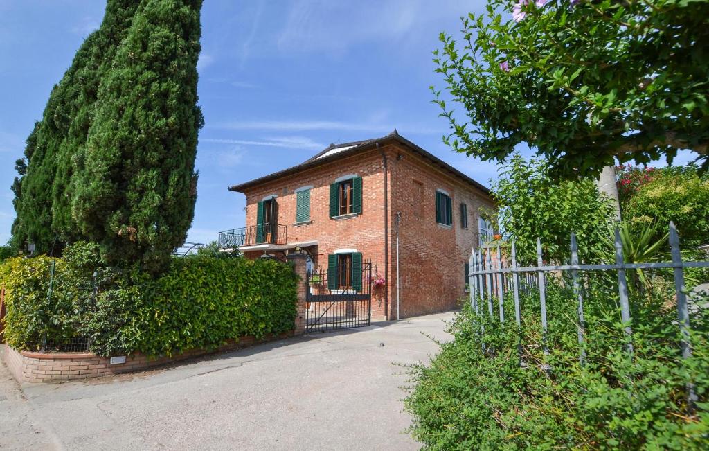a brick house with a fence in front of it at Pet Friendly Home In Sinalunga in Sinalunga