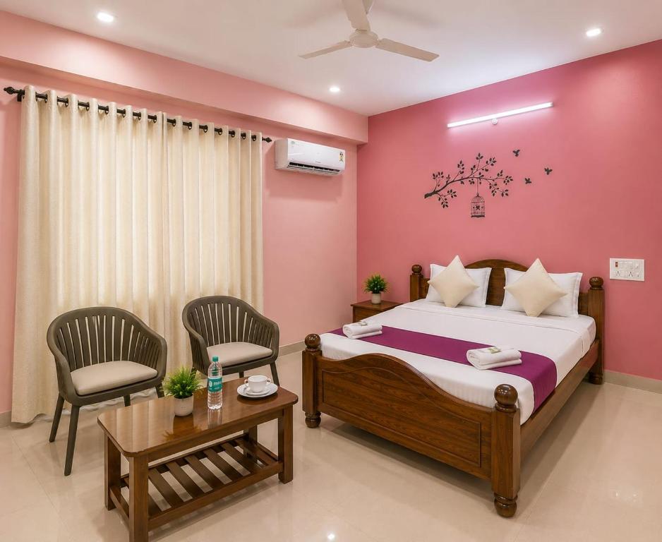 a bedroom with a bed and two chairs and a table at Hotel Golden Suites in Bangalore
