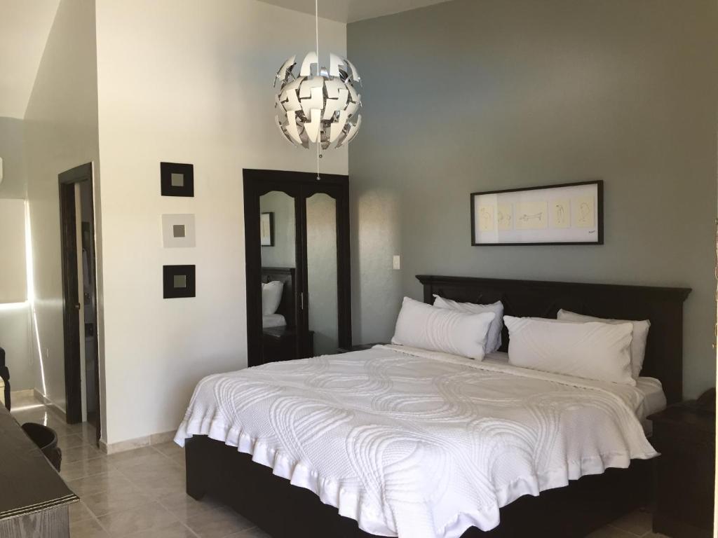 1 dormitorio con 1 cama grande y lámpara de araña en Hotel Las Caobas, en San Francisco de Macorís