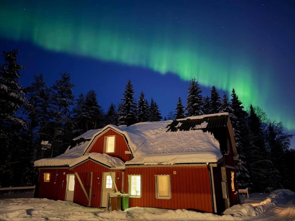eine rote Hütte mit der Aurora am Himmel in der Unterkunft Hej hus! in Nikkala