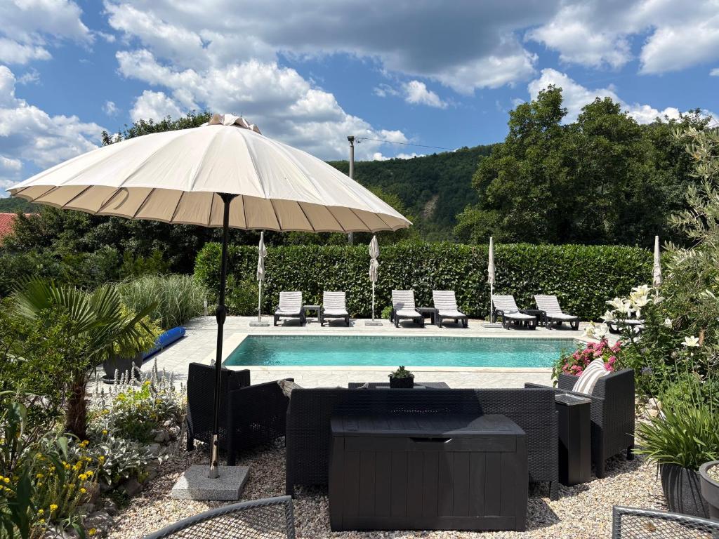 a pool with an umbrella and chairs and a table at Villa Anne A lovely place in the mountains in Brest