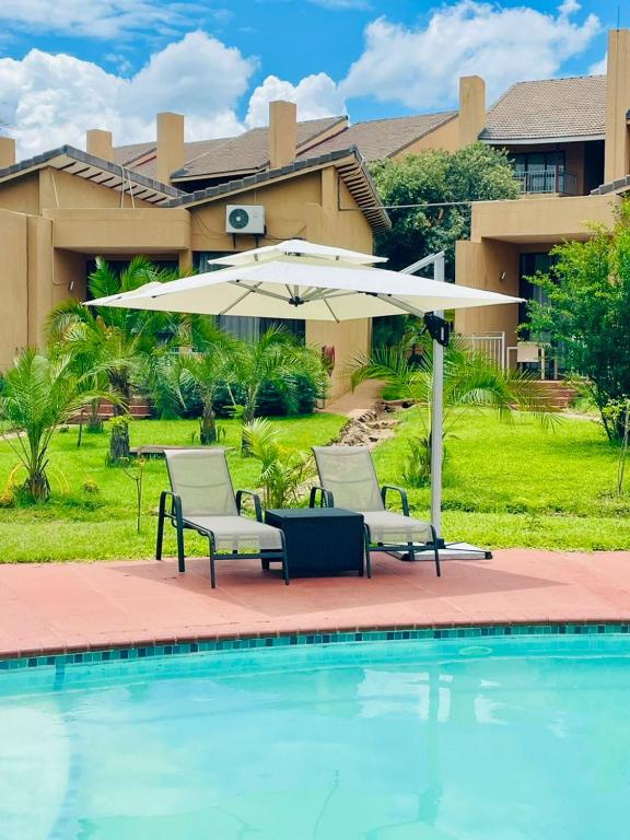 a patio with two chairs and an umbrella next to a pool at Wild View Resort in Kasane