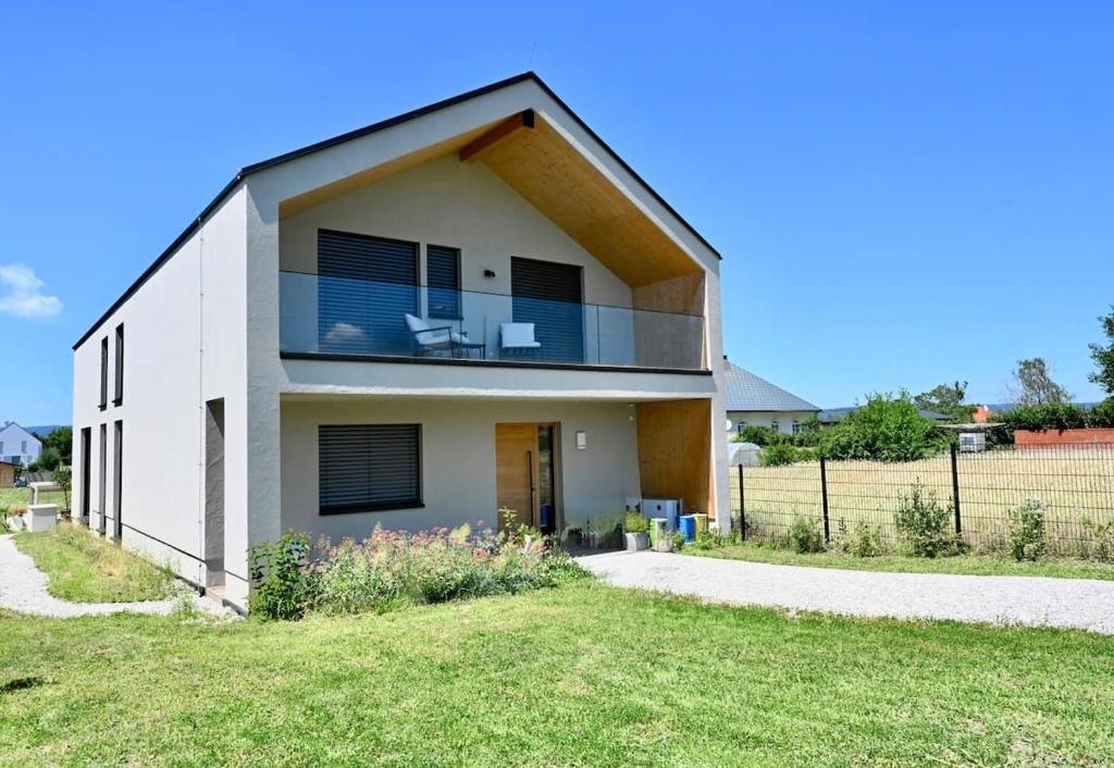 a large white house with a balcony at Architect-Designed Villa with Heated Indoor Pool in Oslip
