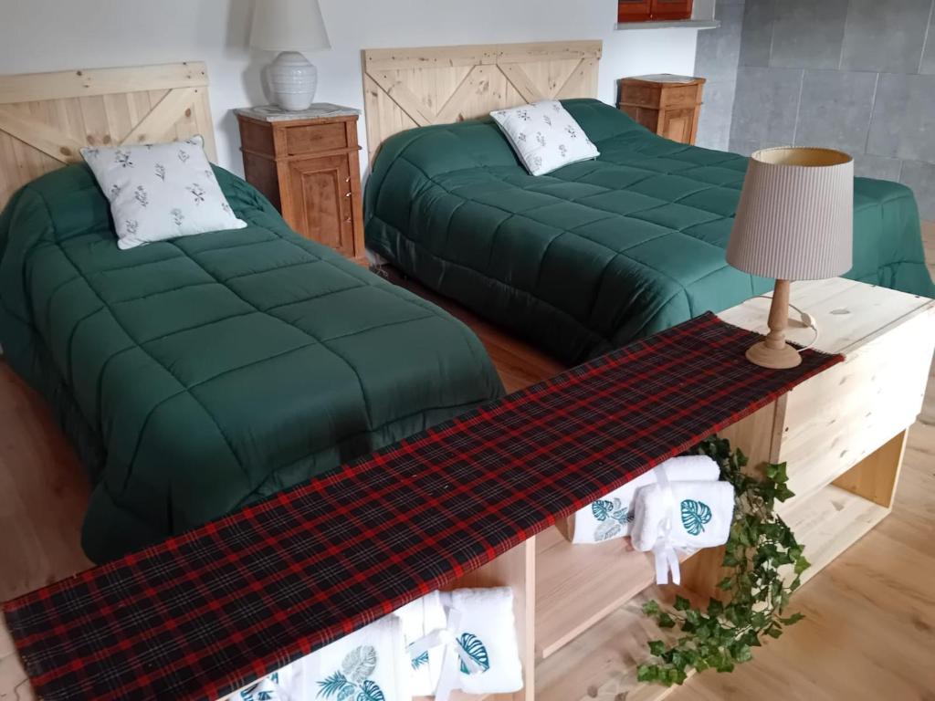 a bedroom with two beds and a table with a lamp at il Bucaneve in Norcen