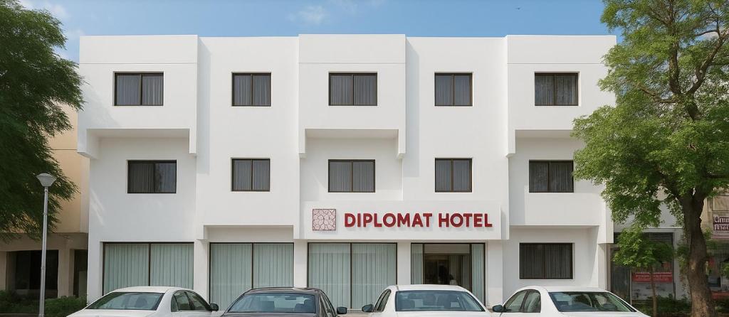 a white building with cars parked in front of it at Diplomat Hotel in Islamabad