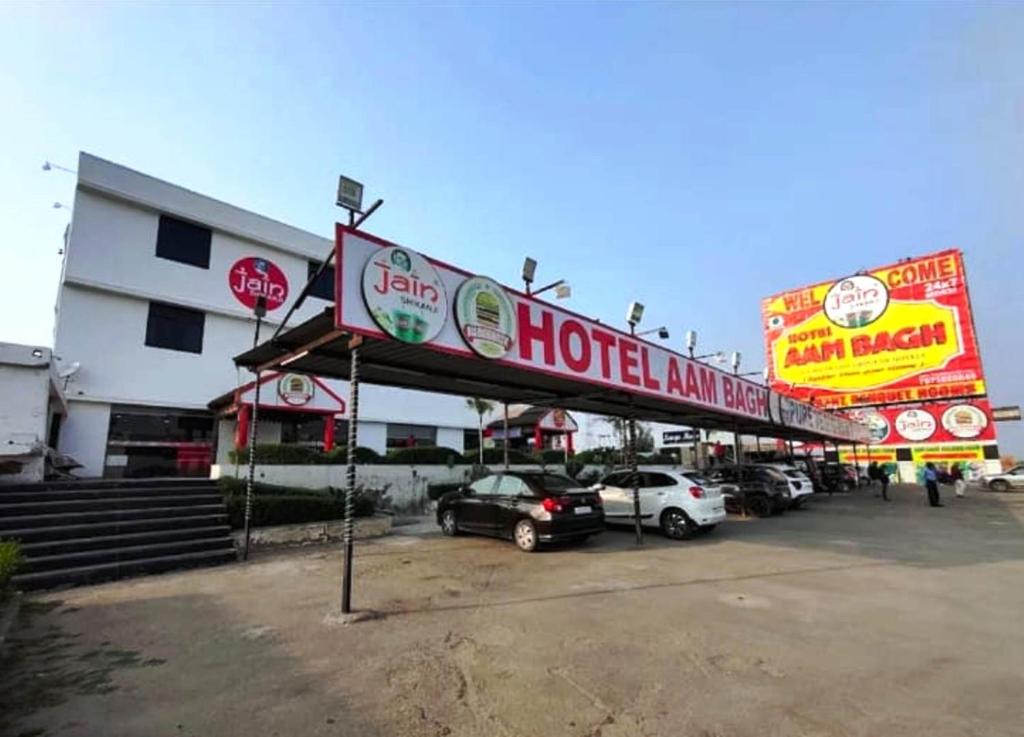 a hotel with cars parked in a parking lot at Hotel Aam Bagh & Jain Shikanji in Kot Pūtli