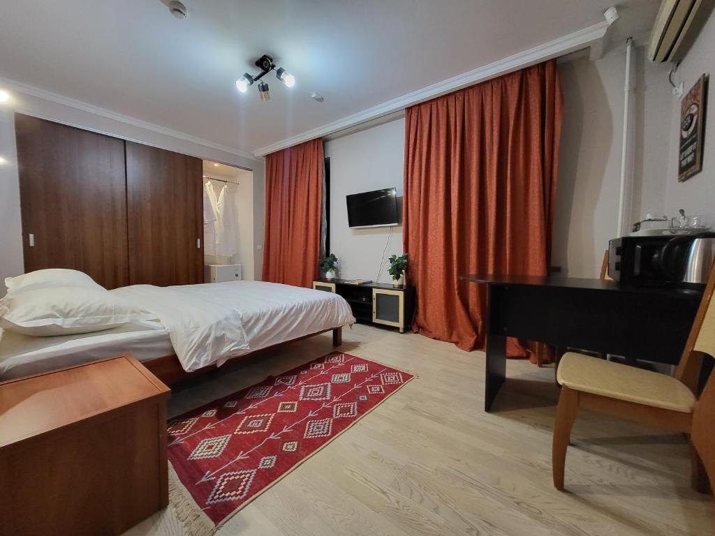 a bedroom with a bed and a desk and a piano at CryptoHotel Park in Almaty