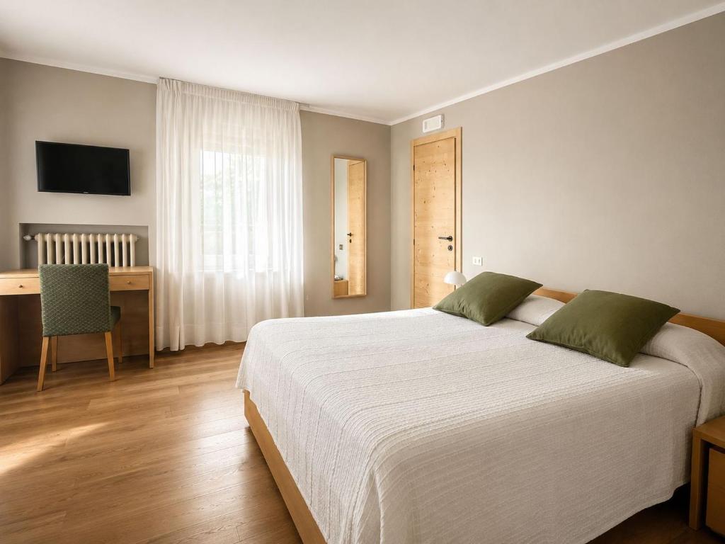 a bedroom with a large white bed and a desk at Albergo Al Laghetto B&B in Asiago