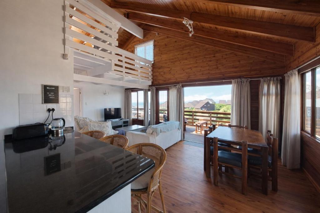 a kitchen and living room with a table and chairs at Beach Cabin with a pool in Port Alfred