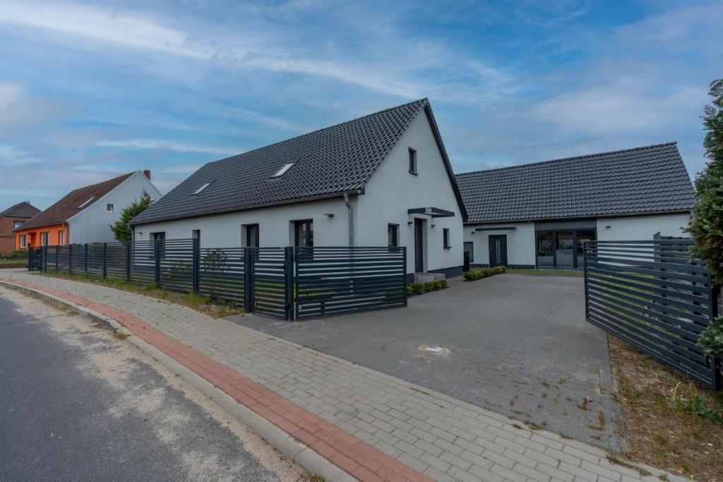 a white house with a black roof and a fence at Lara Prime in Zepkow