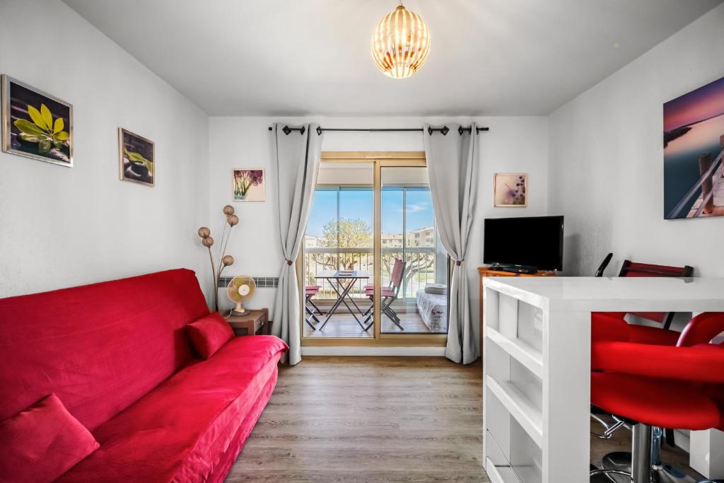 a living room with a red couch and a table at T2 dans résidence arborée in Six-Fours-les-Plages