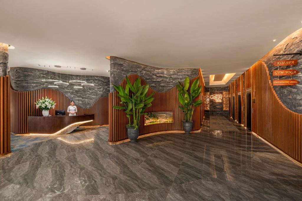 A polished lobby reception with dark stone, timber screens and tropical plants.