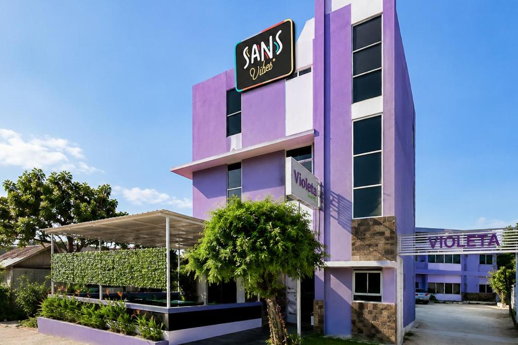 a pink building with a sign on it at SANS Vibes Violeta Inn Jambi in Jambi