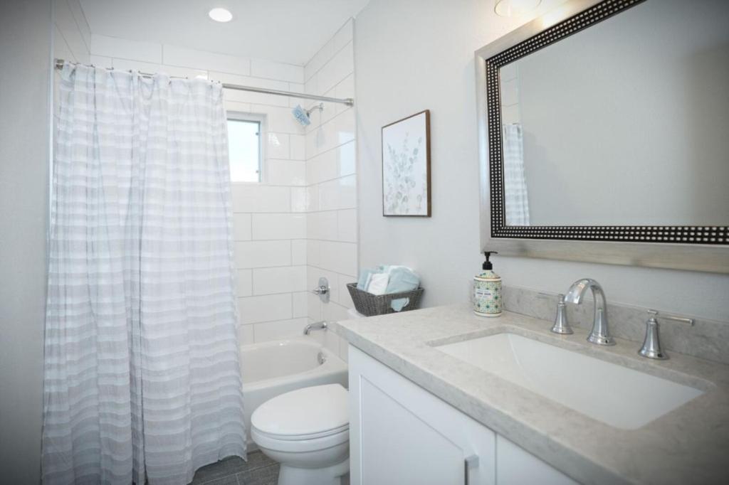 a bathroom with a sink and a toilet and a mirror at Awesome 5 bedroom 3 bath pool home with in-ground jacuzzi in Orange