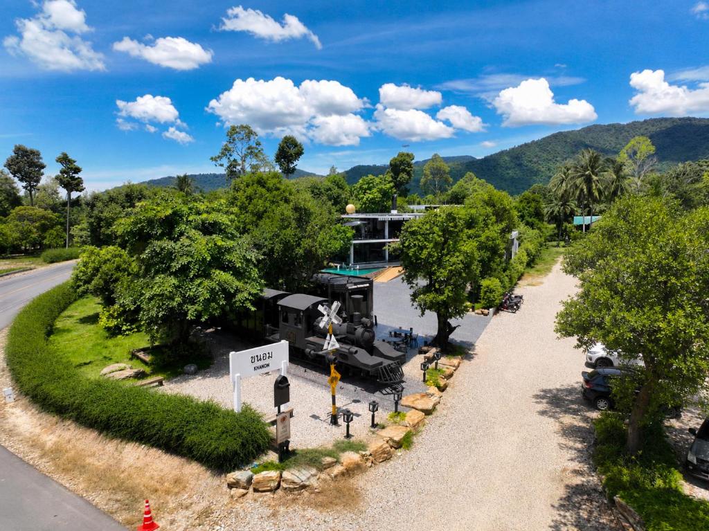 a train on the side of a road next to a house at Khanom Station 549 in Khanom