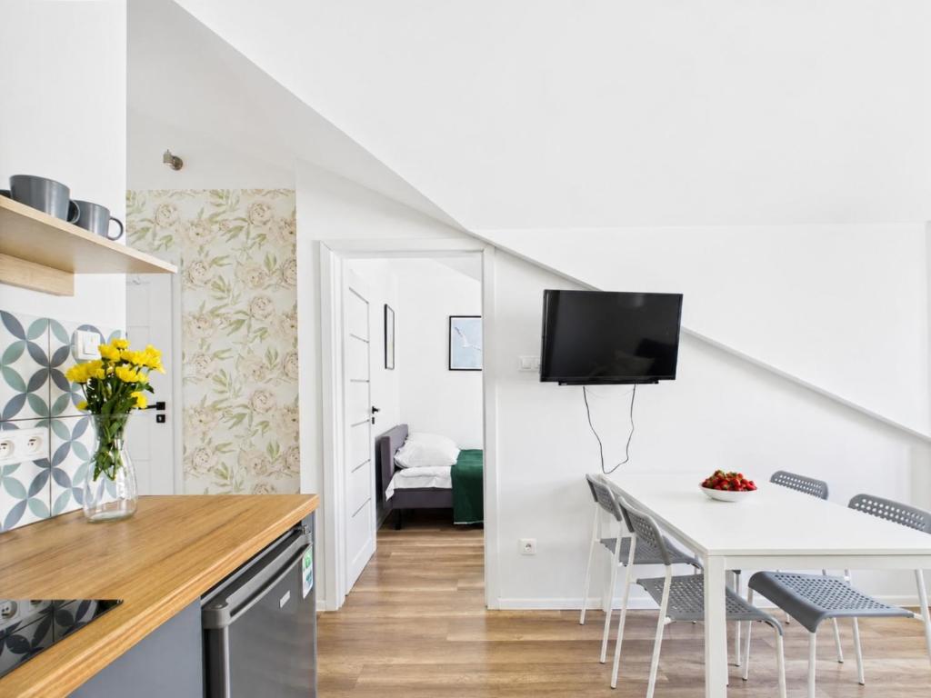 a kitchen and dining room with a white table and chairs at Apartament 44B, Dębina, cichy, 400 m do plaży przez las in Debina