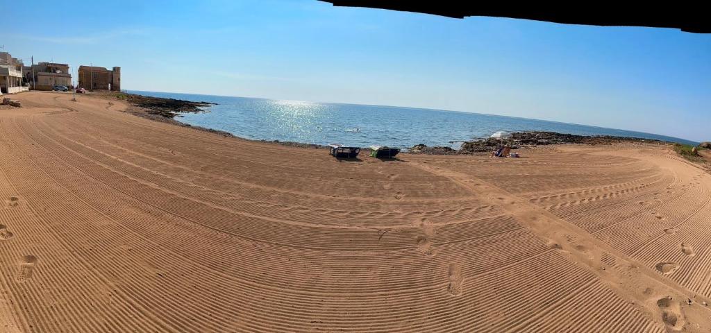 an empty sandy beach with a large body of water at Prima Fila in Calabernardo