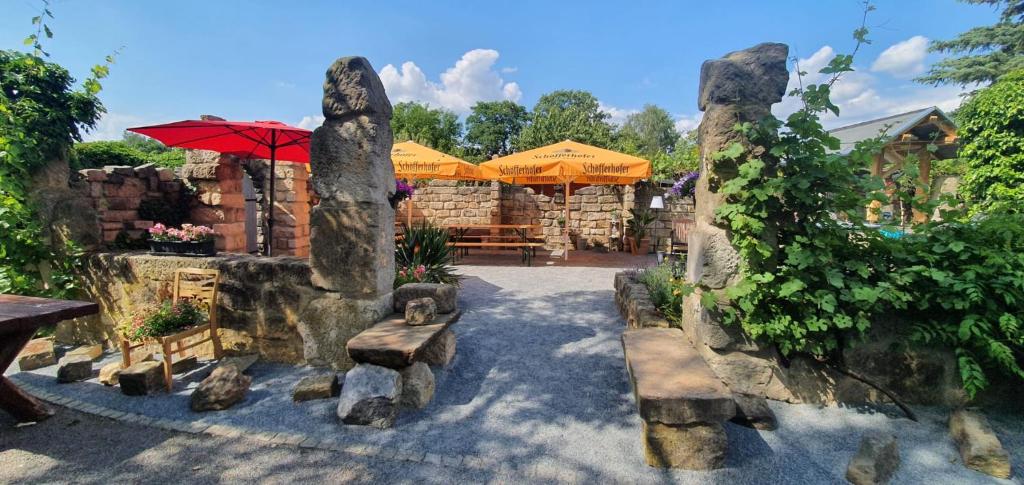 a patio with rocks and an umbrella and benches at Pension Finkenschenke in Gröditz