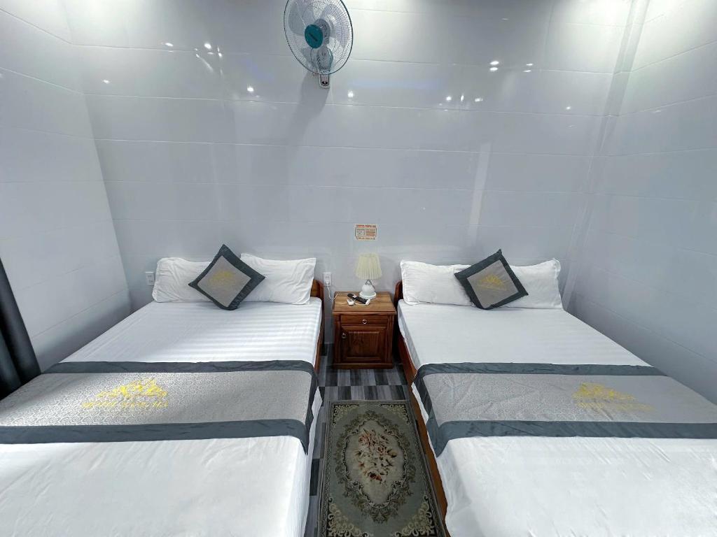 a small room with two beds and a clock on the wall at Hotel Nắng Hạ in Chú Cư
