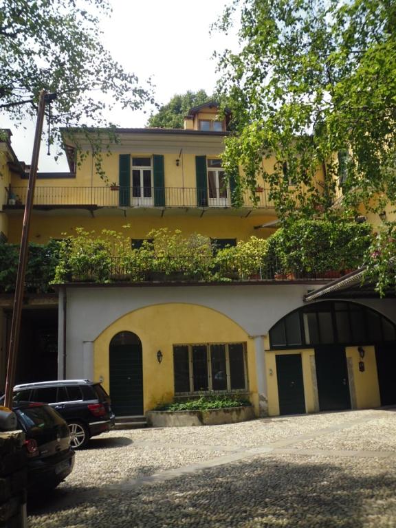a yellow house with a car parked in front of it at Il Platano in Como