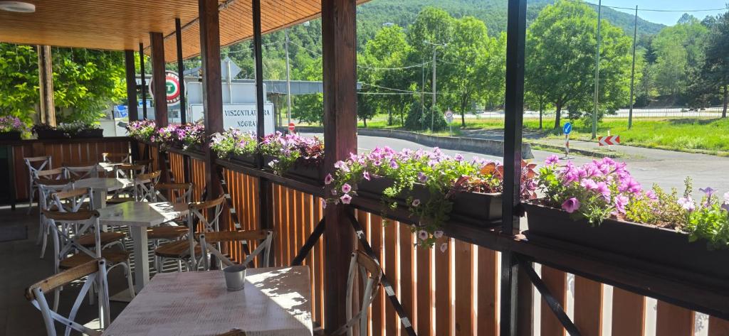 a restaurant with tables and flowers on a fence at Határ Motel in Somoskőújfalu