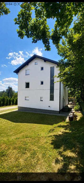 a white building in a yard with a tree at 7- Bedroom Villa in Sarajevo