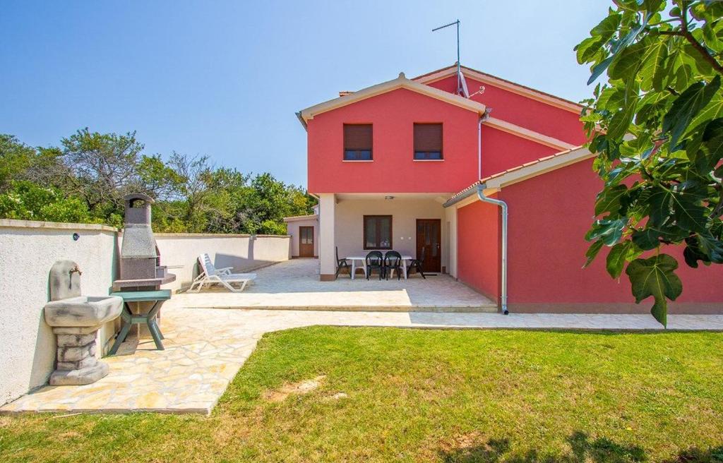 a red house with a statue in front of it at Apartments Racchi in Banjole