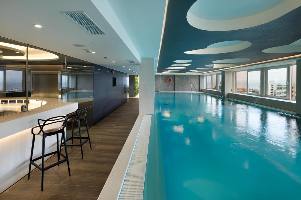a swimming pool with a bar and chairs in a building at Radisson Blu Hotel Olümpia in Tallinn
