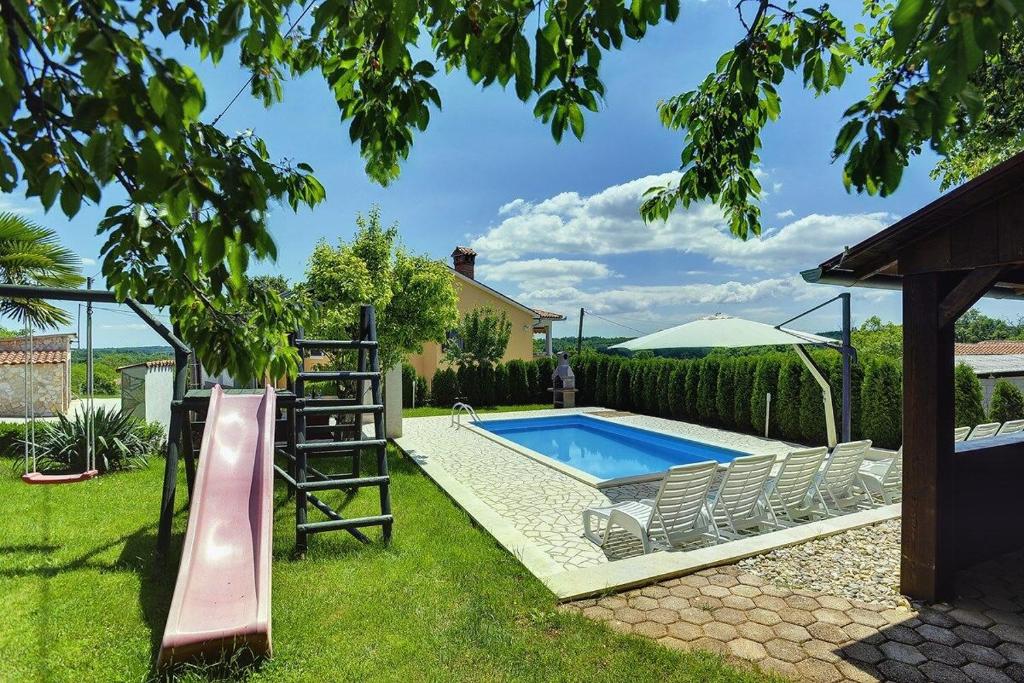 a pool with a slide and a ladder next to a house at Villa Semy in Pazin