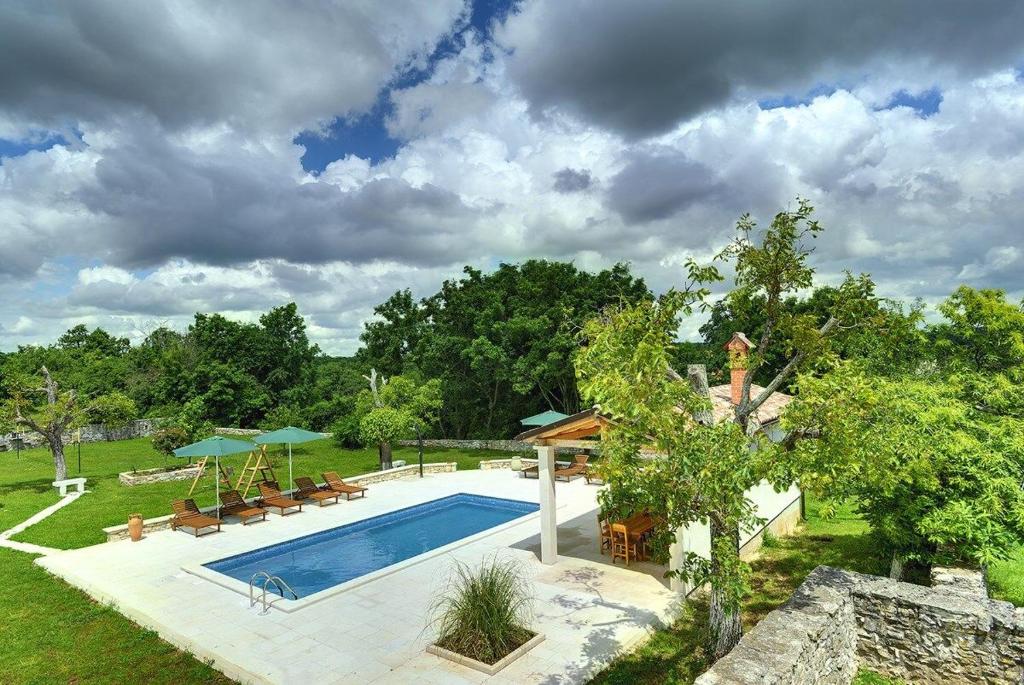 a swimming pool in a yard with chairs and umbrellas at Villa Lucy in Barban