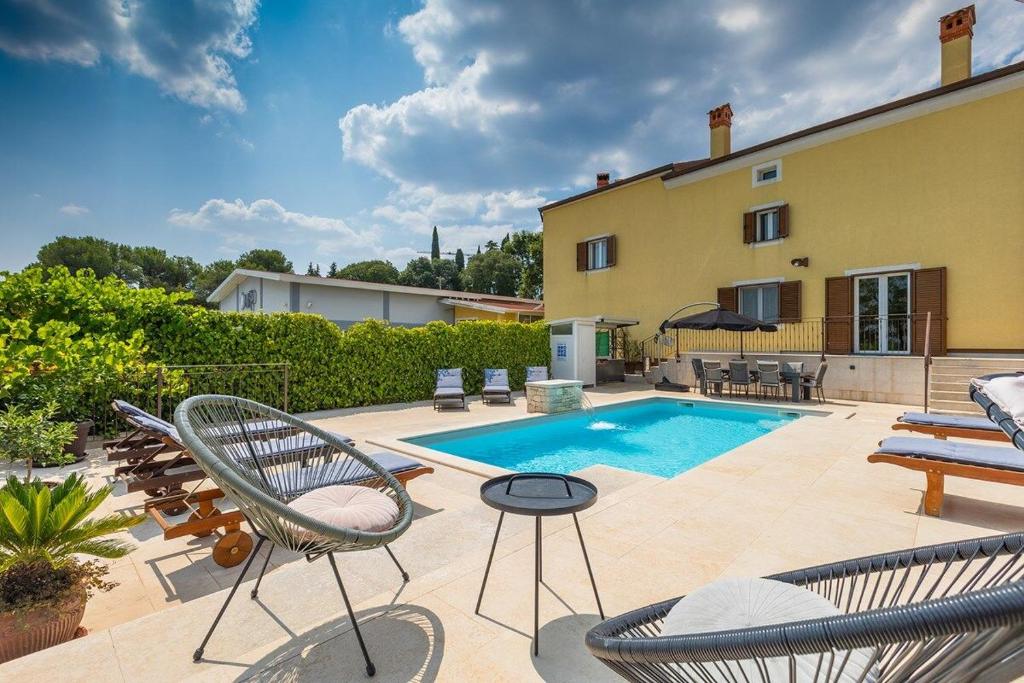 a patio with chairs and a swimming pool at House Casa Alberta in Rovinjsko Selo